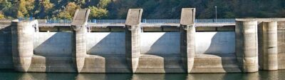 Detalle de los pilares de hormigón y el muro de la presa en la central hidroeléctrica de Salime, perteneciente a Saltos del Navia en Asturias, con vegetación de fondo.