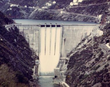 Fotografía histórica de la presa de Salime en el río Navia, Asturias, mostrando el agua cayendo por los aliviaderos entre laderas escarpadas.