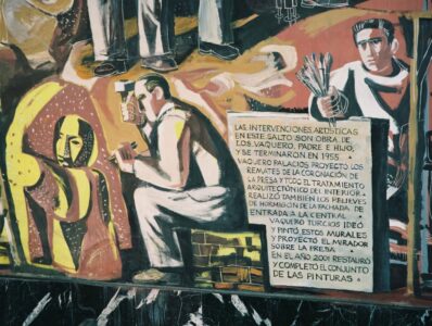 Detalle del mural en la Central de Salime pintado por Joaquín Vaquero Turcios, que muestra a los artistas trabajando y un texto explicativo sobre el patrimonio artístico de los Saltos del Navia.